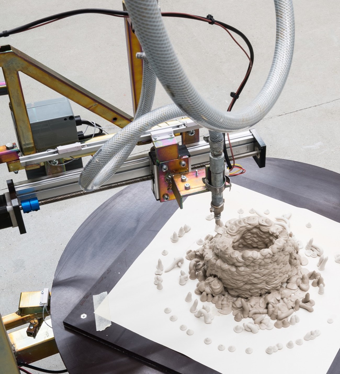 Henrik Menné: L5, 2021, iron, wood, motor, sausage press, compressed air hoses, electronics and clay, 260h x 160w x 10d cm (installation view).